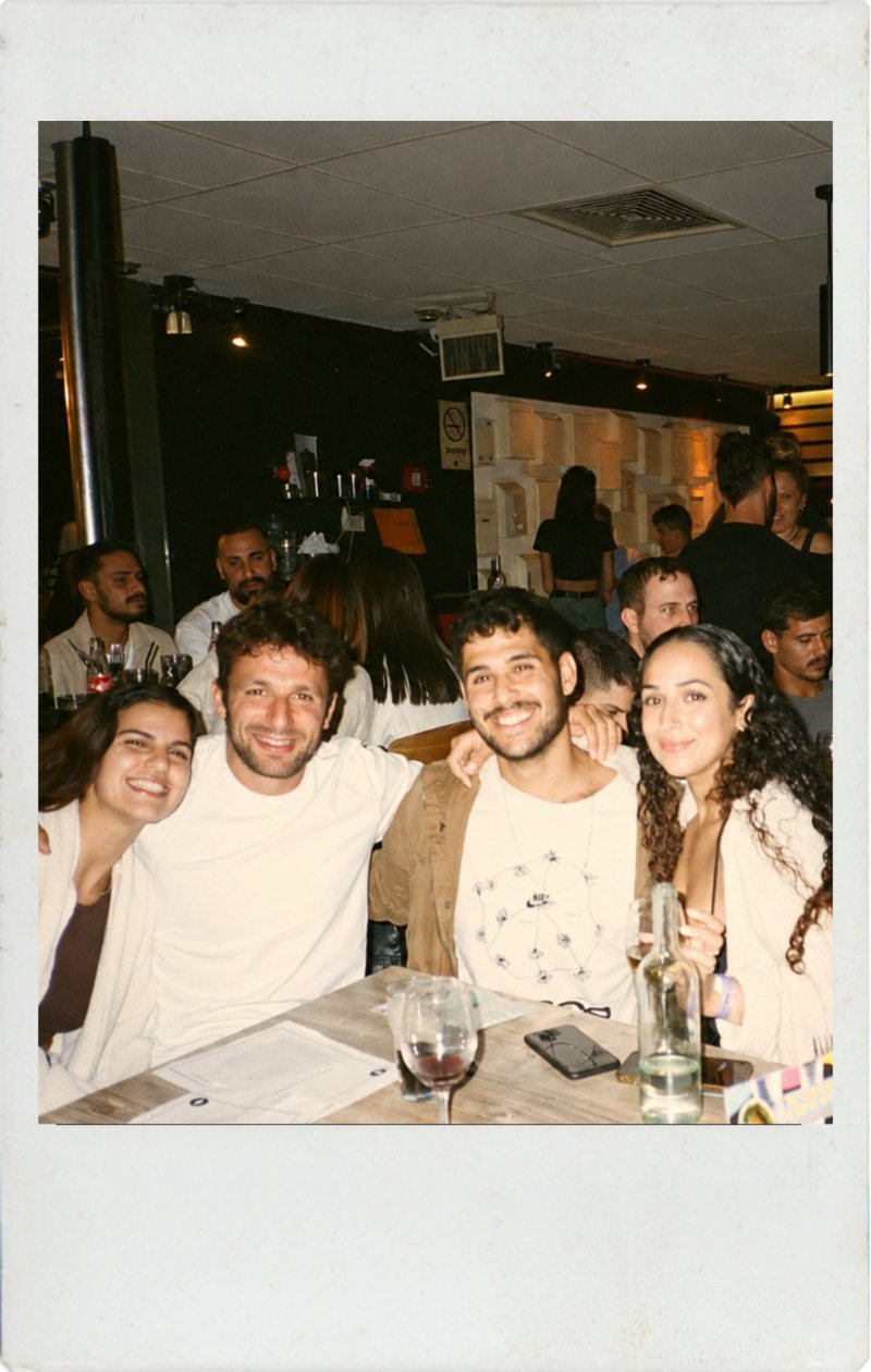 six people clinking wine glasses at a candlelit dinner